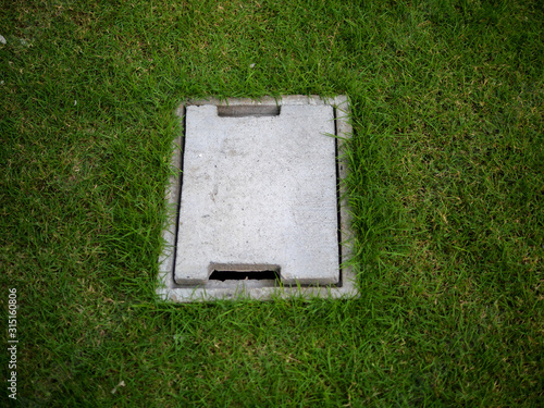 Manhole in a garden, place on a green grass