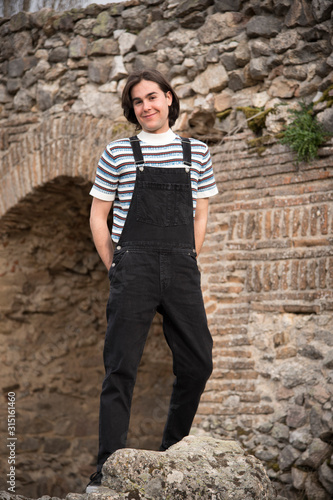 Fototapeta Naklejka Na Ścianę i Meble -  Young man posing in the field and with a bridge in the background. Enjoying the outdoors