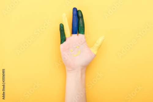 cropped view of woman with colorful fingers showing palm isolated on yellow