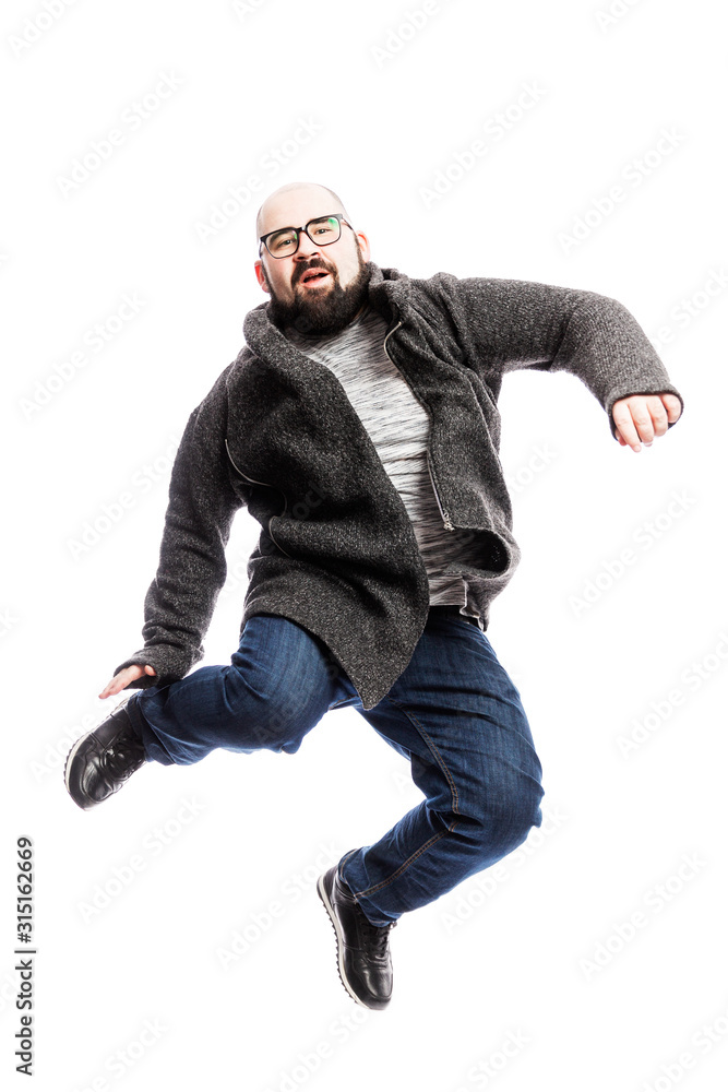 A bald man with glasses and a beard is jumping. Isolated over white background. Vertical.