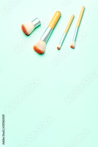 Various makeup brushes on pastel background, copy space, top view. Beauty treatment, self care background, flat lay