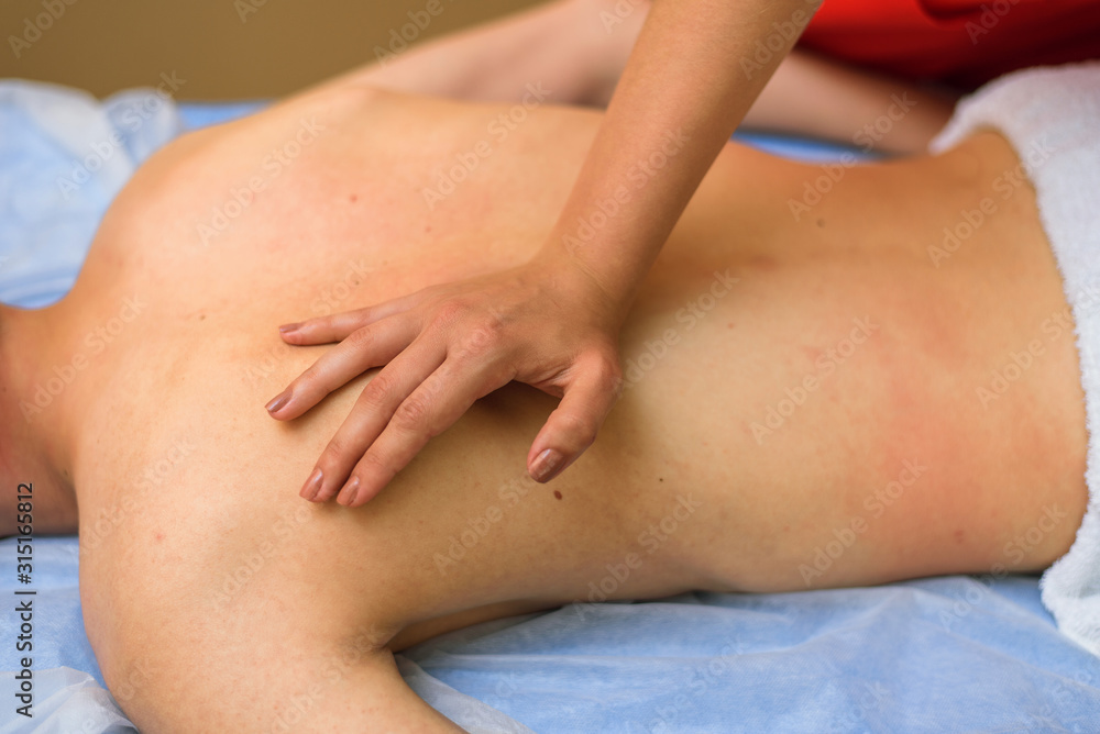 Masseur wrinkles back to client. Back massage for a young man Masseur wrinkles back to client. Back massage for a young man