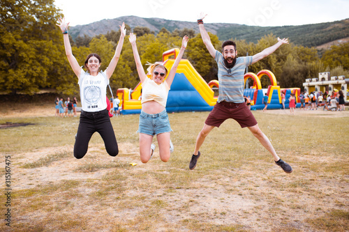 Adult friends jumping and having fun near the bouncy castle in the countryside. Fun concept.