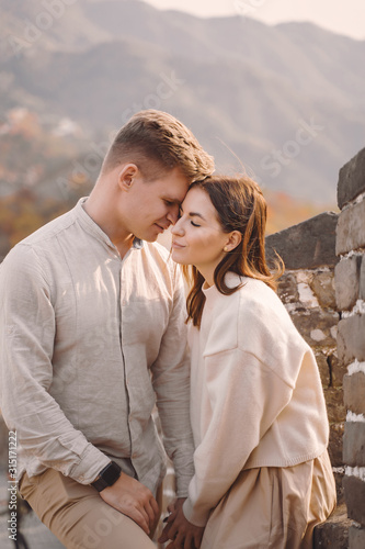 beautiful young couple hugging at the Great Wall of China. Newly married couple on their honemoon to Great Wall near Beijing China. Stylish couple exploring one of the wonders of the world. photo