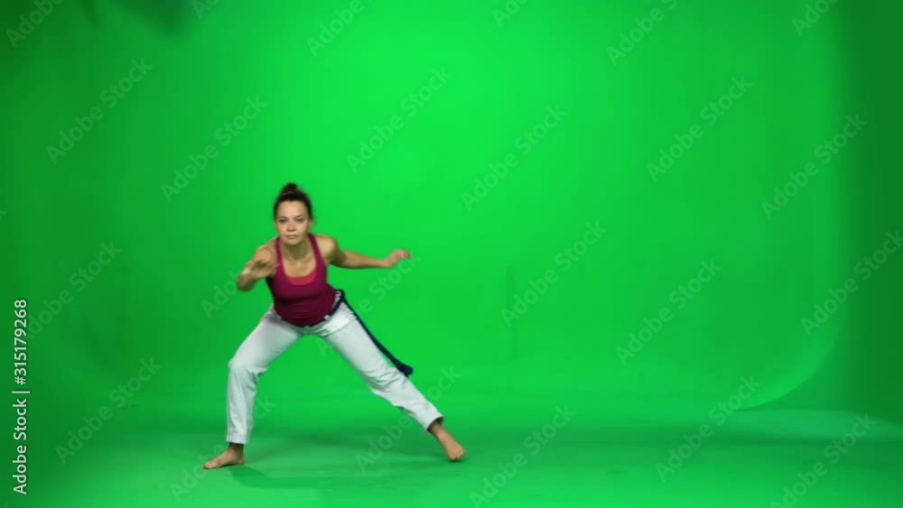 Brunette female practicing capoeira on green screen. Slow motion. Brunette female practicing capoeira on green screen. Slow motion.