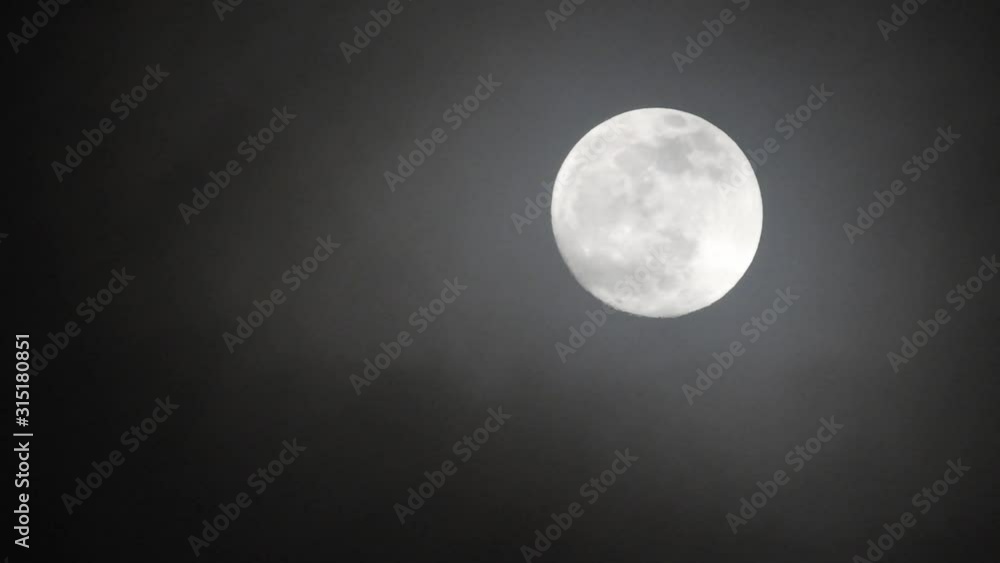 Full moon on dark cloudy night. Clouds passing by the moon, real time shot. Full moon on dark cloudy night. Clouds passing by the moon, real time shot.