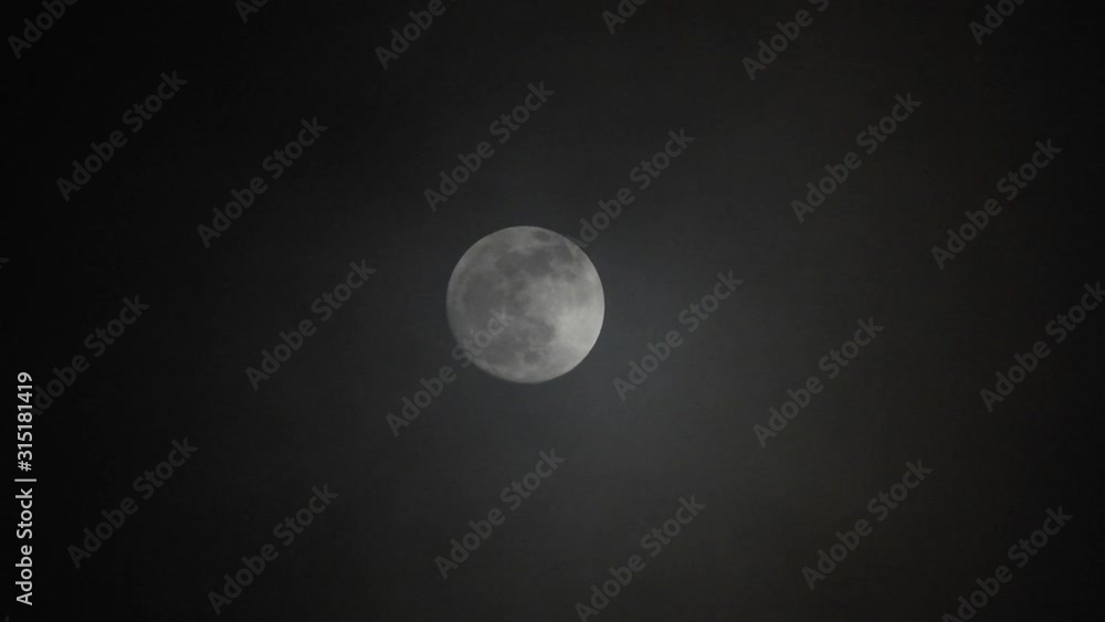 Full moon on dark cloudy night. Clouds passing by the moon, real time shot. Full moon on dark cloudy night. Clouds passing by the moon, real time shot.