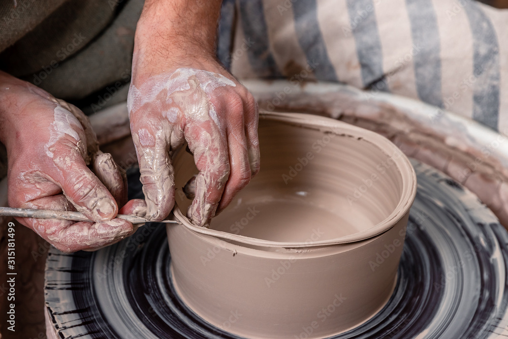 Potter making a bowl of white clay on the potter's wheel circle in studio, concept of creativity and art, horizontal photo