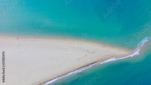 The end of the golden sandy beach and turquoise sea on the both sides 