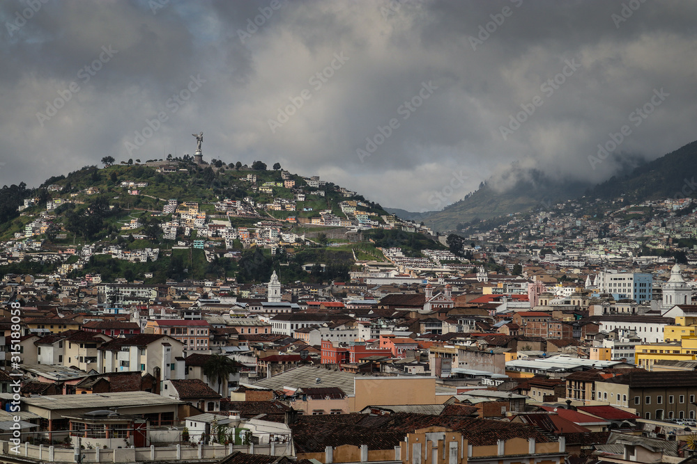 Panorama of the city of Quito in Ecuador. Looking towards the southern hills and a statue of quito, overlooking the city houses.