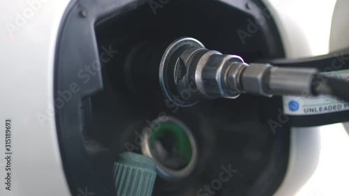 Gas man putting natulal gas in the car's gas tank of a white ecologic methane fueled car at a cng pump. Shot in 6k. photo