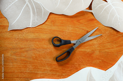 scissors on a wooden table, paper with decorative elements for interior design of an apartment, top view