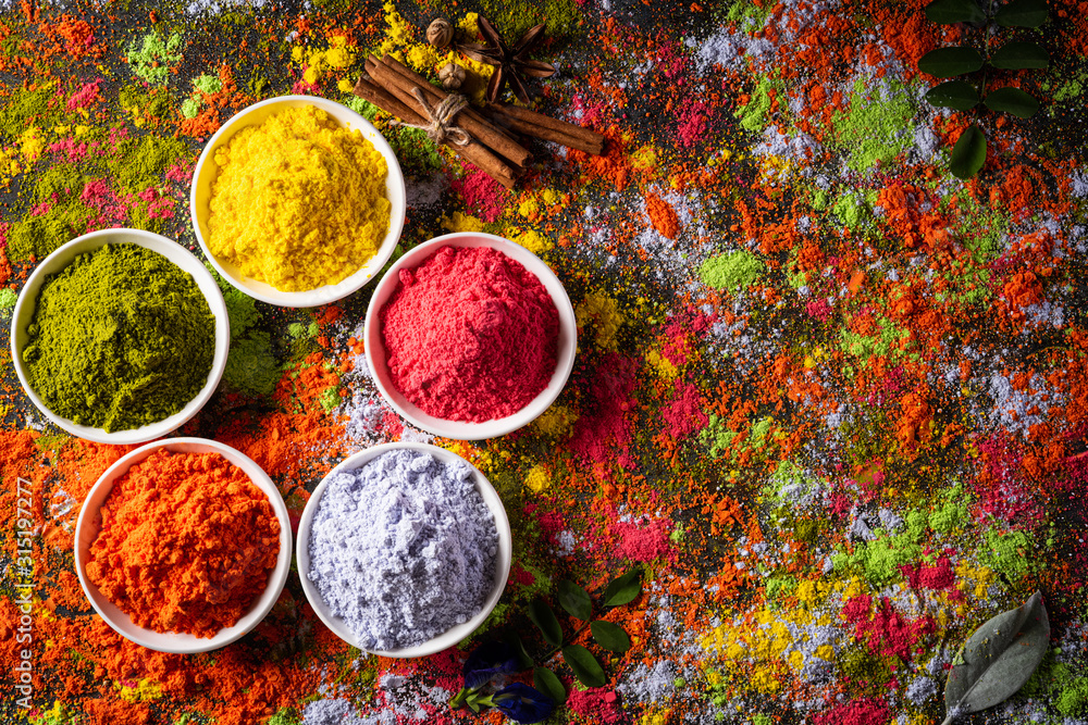Holi festival celebration. Traditional Indian Holi colours powder decoration with paints. Top view of Organic Gulal colors in bowls, spices, rustic background for Holi festival.