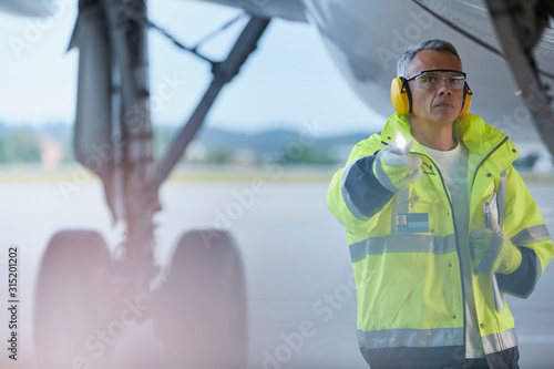 Air traffic controller flashlight under airplane on airport tarmac photo