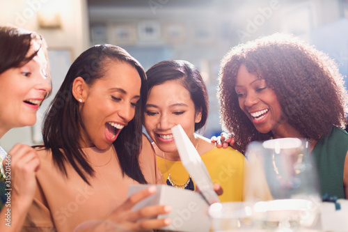 Friends watching woman open birthday gift