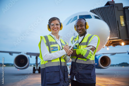 Portrait confident air traffic control ground crew workers near airplane on airport tarmac photo