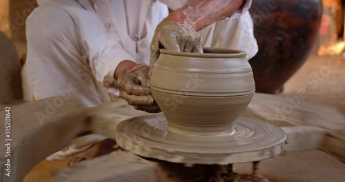 Skilled hands of potter shaping the clay on potter wheel and sculpting clay pot jar. Shilpagram, Udaipur, Rajasthan, India photo