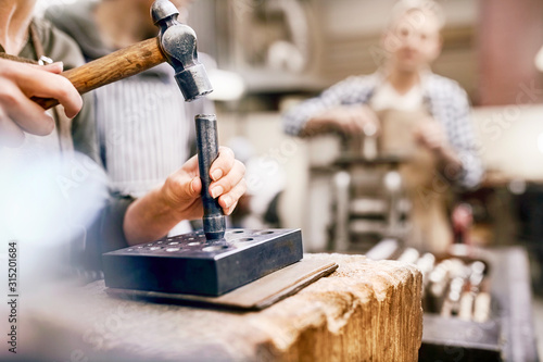 Jeweler using hammer and equipment in workshop photo