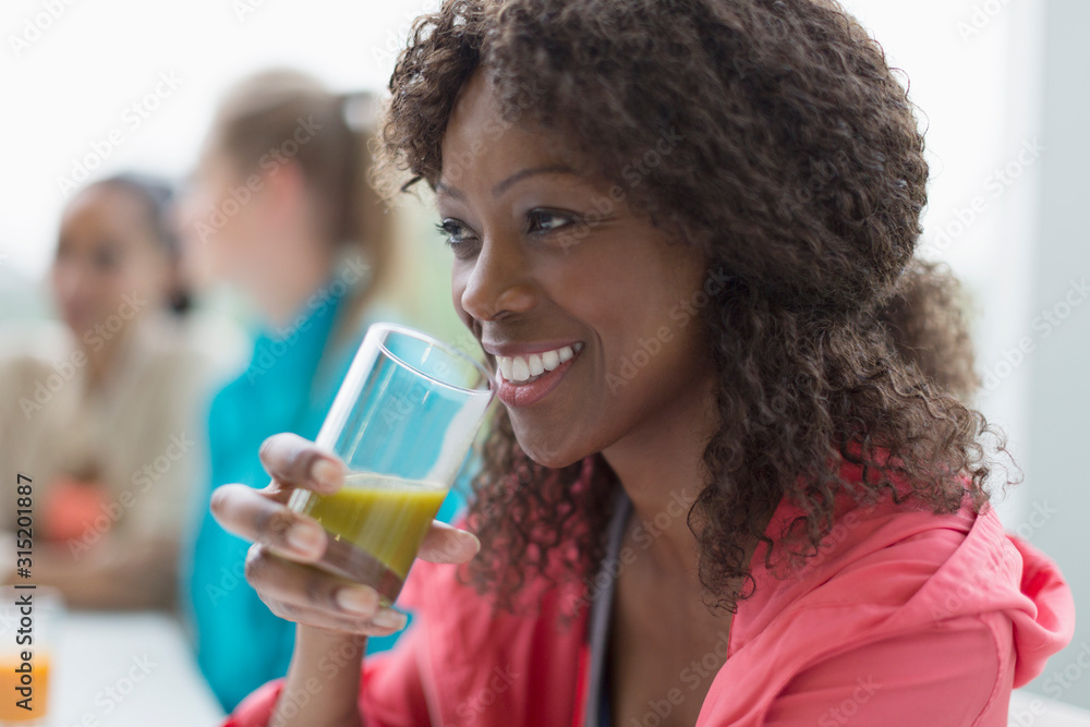 Smiling woman drinking healthy green smoothie in cafe post workout Smiling woman drinking healthy green smoothie in cafe post workout