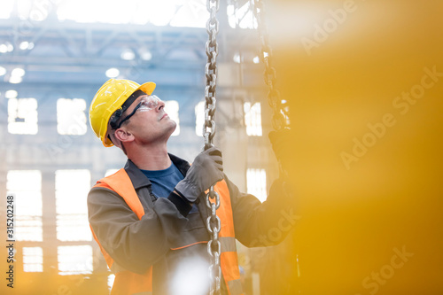 Steel worker holding chain in factory