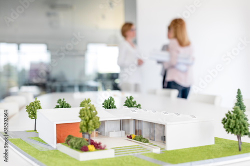 Female architects talking behind building model