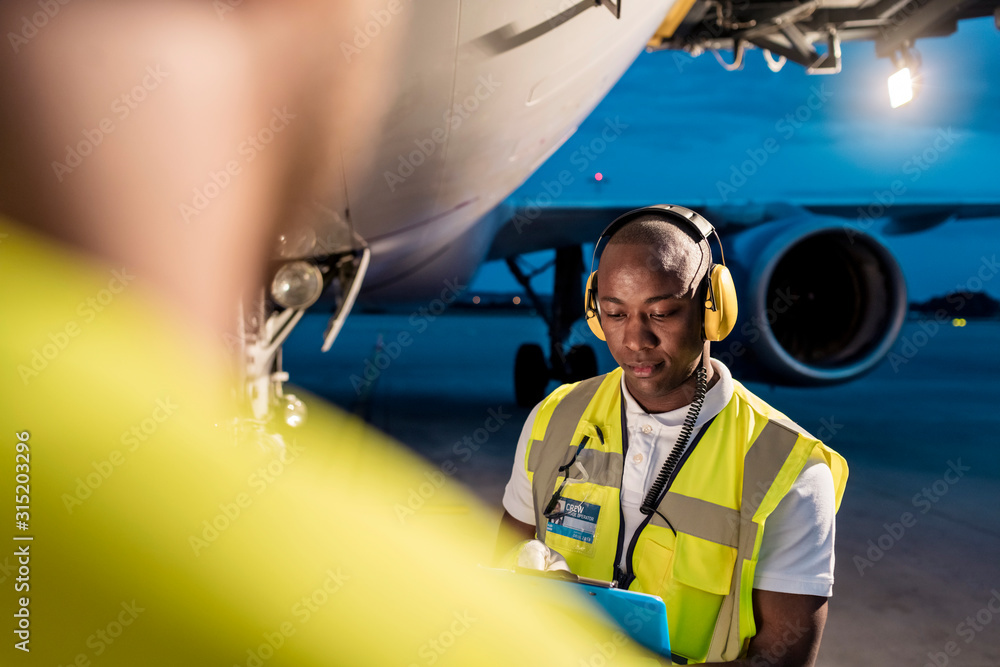Air traffic control ground crew working under airplane on airport