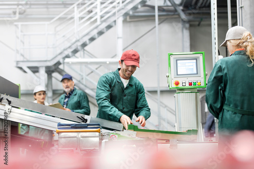 Smiling worker at conveyor belt in food processing plant
