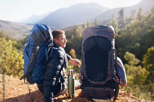 Young couple with backpacks hiking, taking a coffee break photo