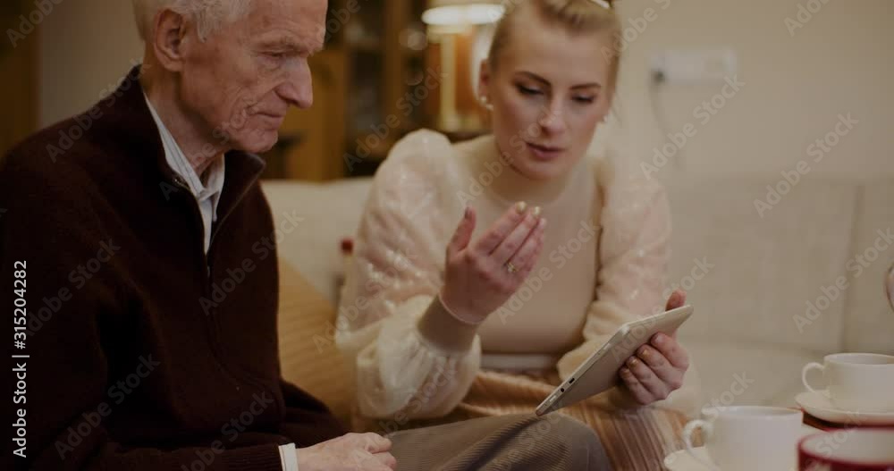 Senior Man Talking While Granddaughter Holding Digital Tablet At Home Senior Man Talking While Granddaughter Holding Digital Tablet At Home