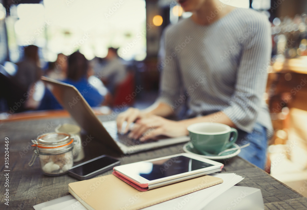 Creative businesswoman working at laptop behind digital tablet in cafe Creative businesswoman working at laptop behind digital tablet in cafe