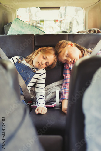 Tired sisters sleeping in back seat of car photo