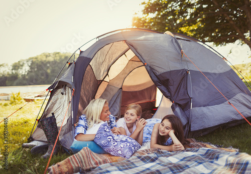 Mother and daughters talking and relaxing in tent at campsite photo