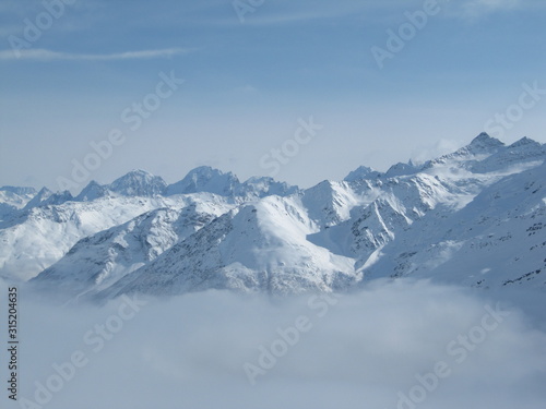 Mountain range above layer of white clouds. beautiful scenery © Yulia