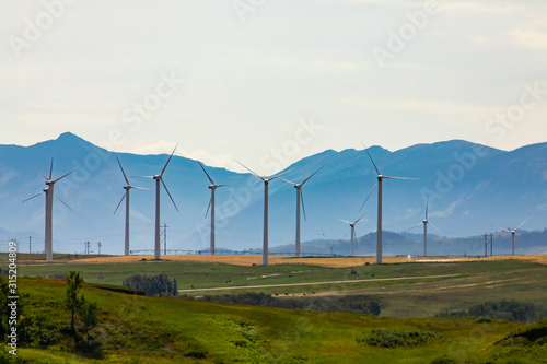 A large wind turbine farm is seen by the Rocky Mountains in Alberta, Canada. Clean renewable and green energy in natural landscape with copy space