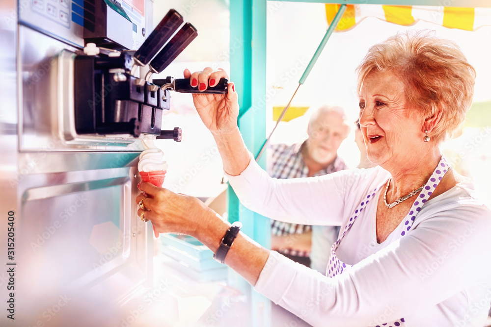 Senior female business owner serving ice cream at food cart Senior female business owner serving ice cream at food cart