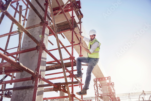 Construction worker climbing rebar at sunny construction site photo