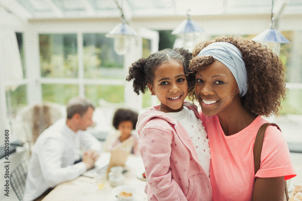Portrait smiling mother and daughter hugging in kitchen Portrait smiling mother and daughter hugging in kitchen
