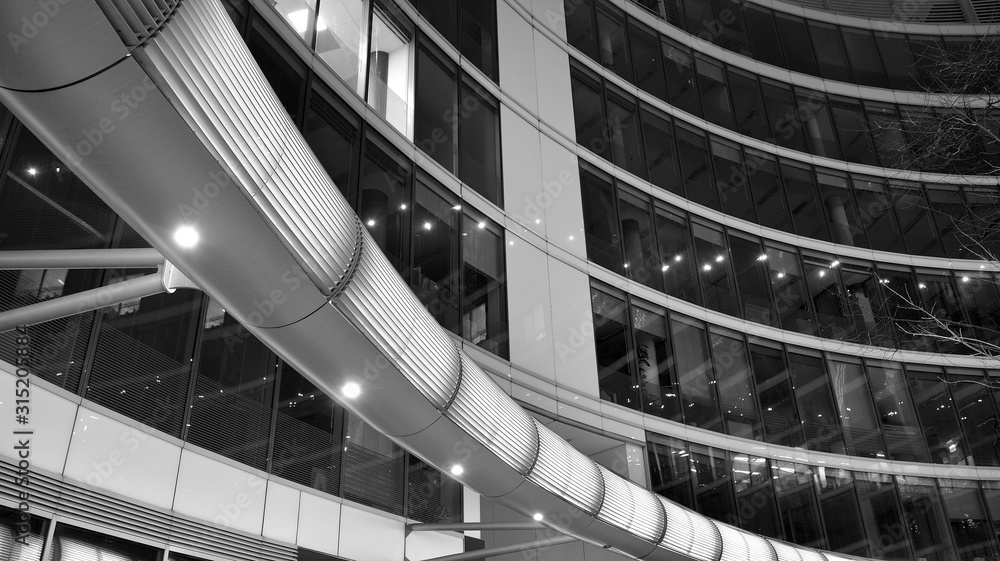 Fototapeta premium Night architecture - building with glass facade. Business district. Concept of economics, financial. Photo of commercial office building exterior. Abstract image of office building. Black and white.