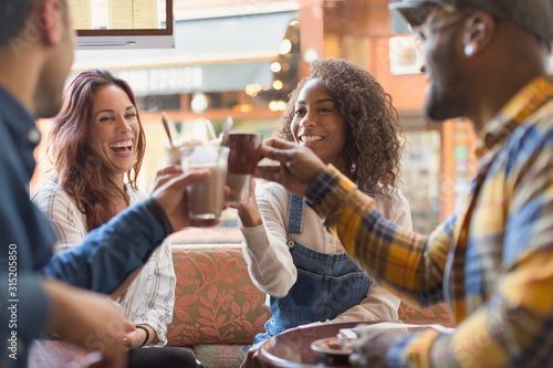 Smiling friends toasting coffee cups in cafe photo