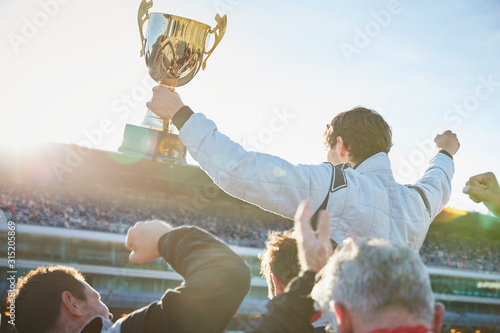 Formula one racing team carrying driver trophy on shoulders, celebrating victory photo