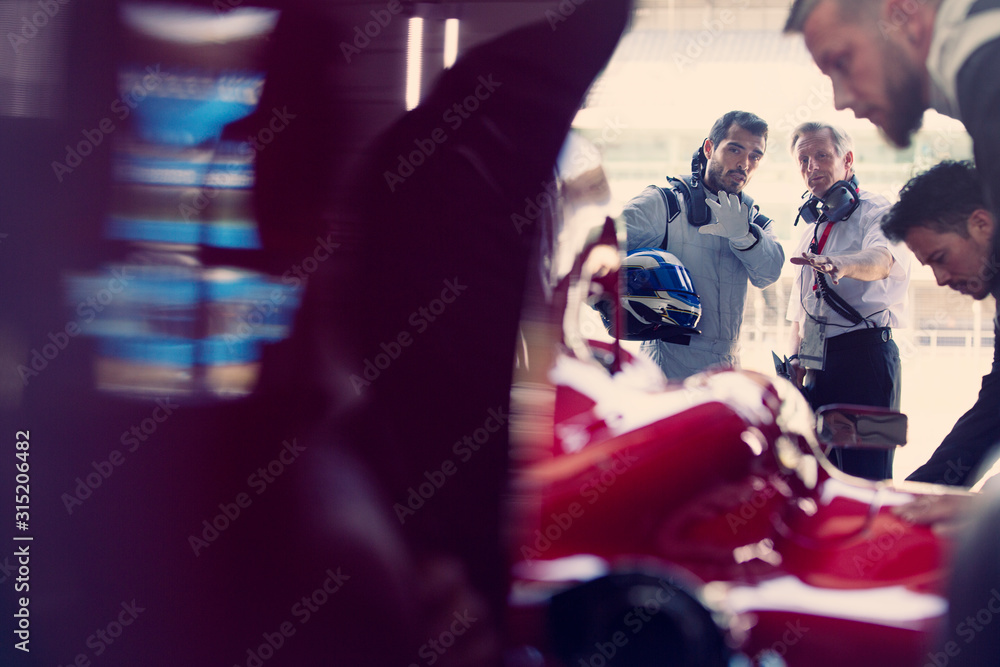 Manager and formula one race car driver talking in repair garage Manager and formula one race car driver talking in repair garage