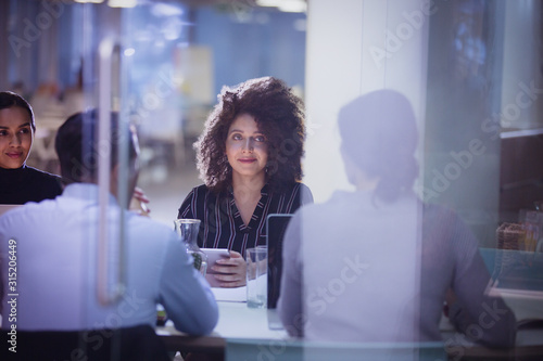 Businesswoman listening in dark conference room meeting photo