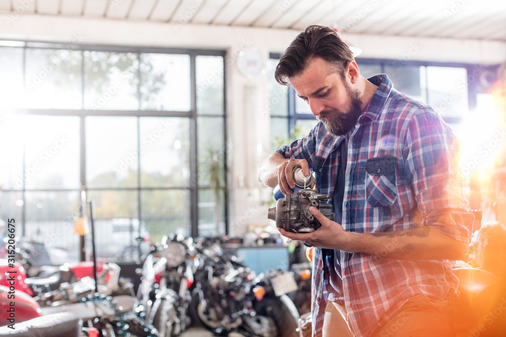 Motorcycle mechanic greasing engine part in workshop Motorcycle mechanic greasing engine part in workshop