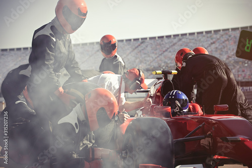 Pit crew replacing tires on formula one race car in pit lane photo