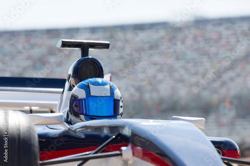 Formula one race car driver wearing helmet on sports track