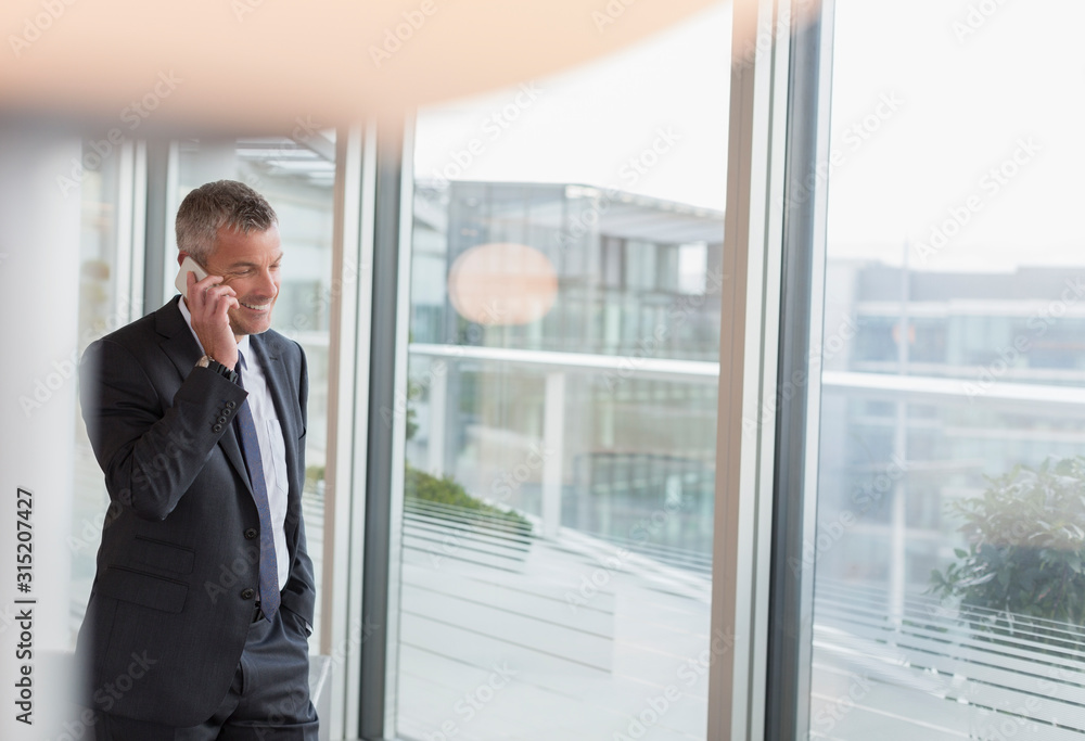 Businessman talking on cell phone at office window Businessman talking on cell phone at office window