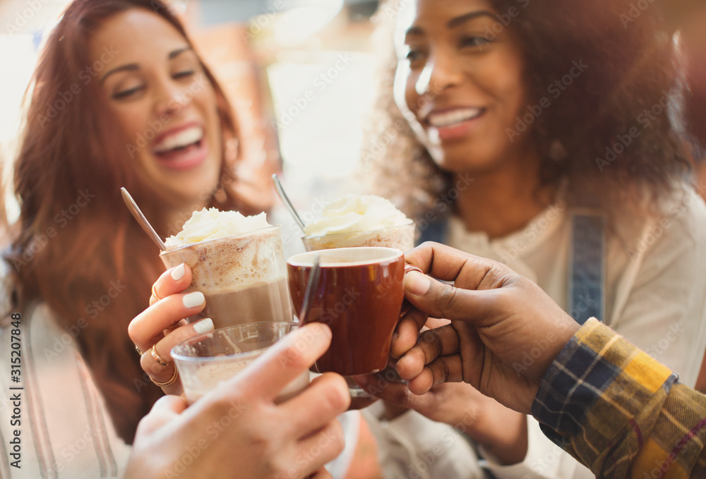 Smiling friends toasting milkshakes and coffee cups in cafe Smiling friends toasting milkshakes and coffee cups in cafe