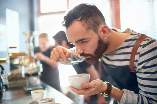 Male coffee roaster tasting coffee photo