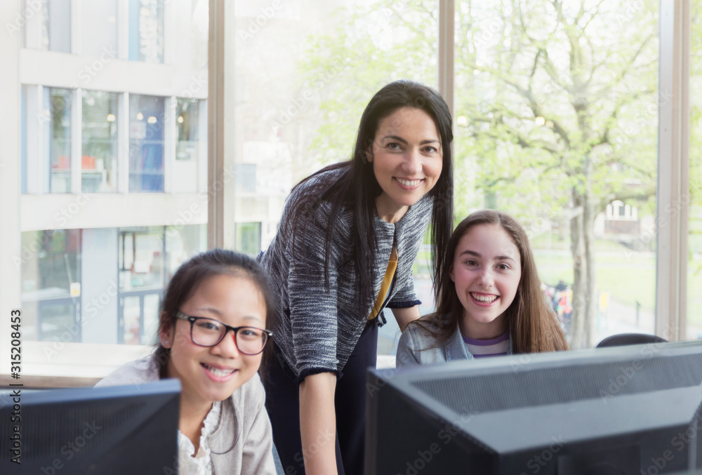 Portrait confident, smiling female teacher girl students researching at computer in library Portrait confident, smiling female teacher girl students researching at computer in library