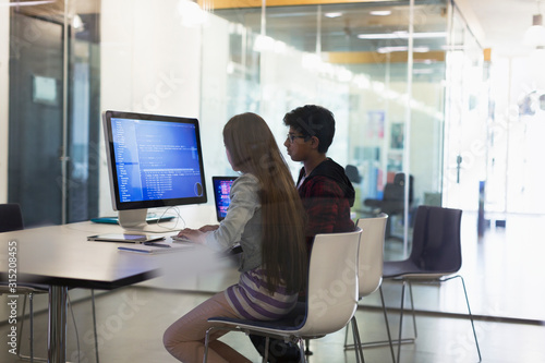 Students programming at computer in classroom photo